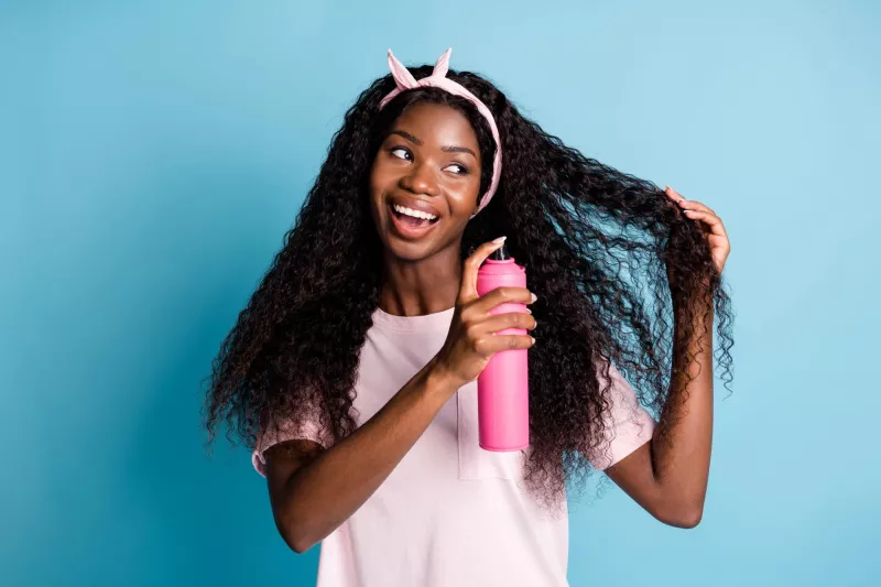 Photo of woman using aerosol product in her long hair