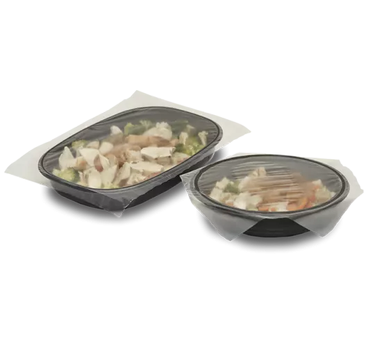 Two black CPET frozen meal trays with food and a clean lidding film over the top
